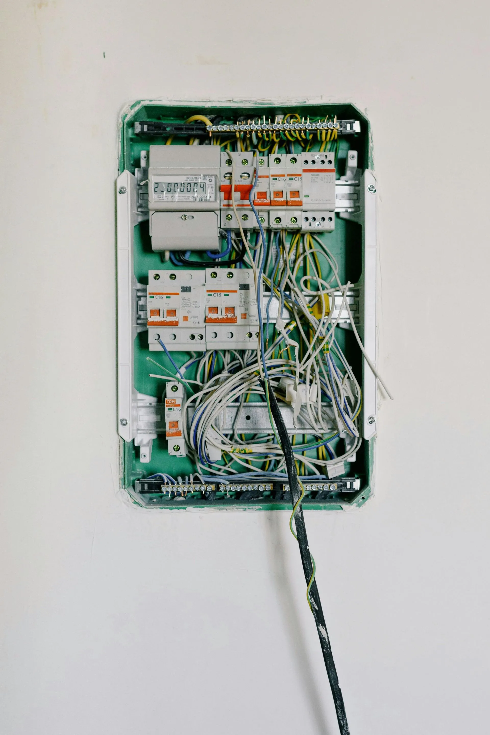 Open distribution board with circuit breakers and wiring mounted on a white wall