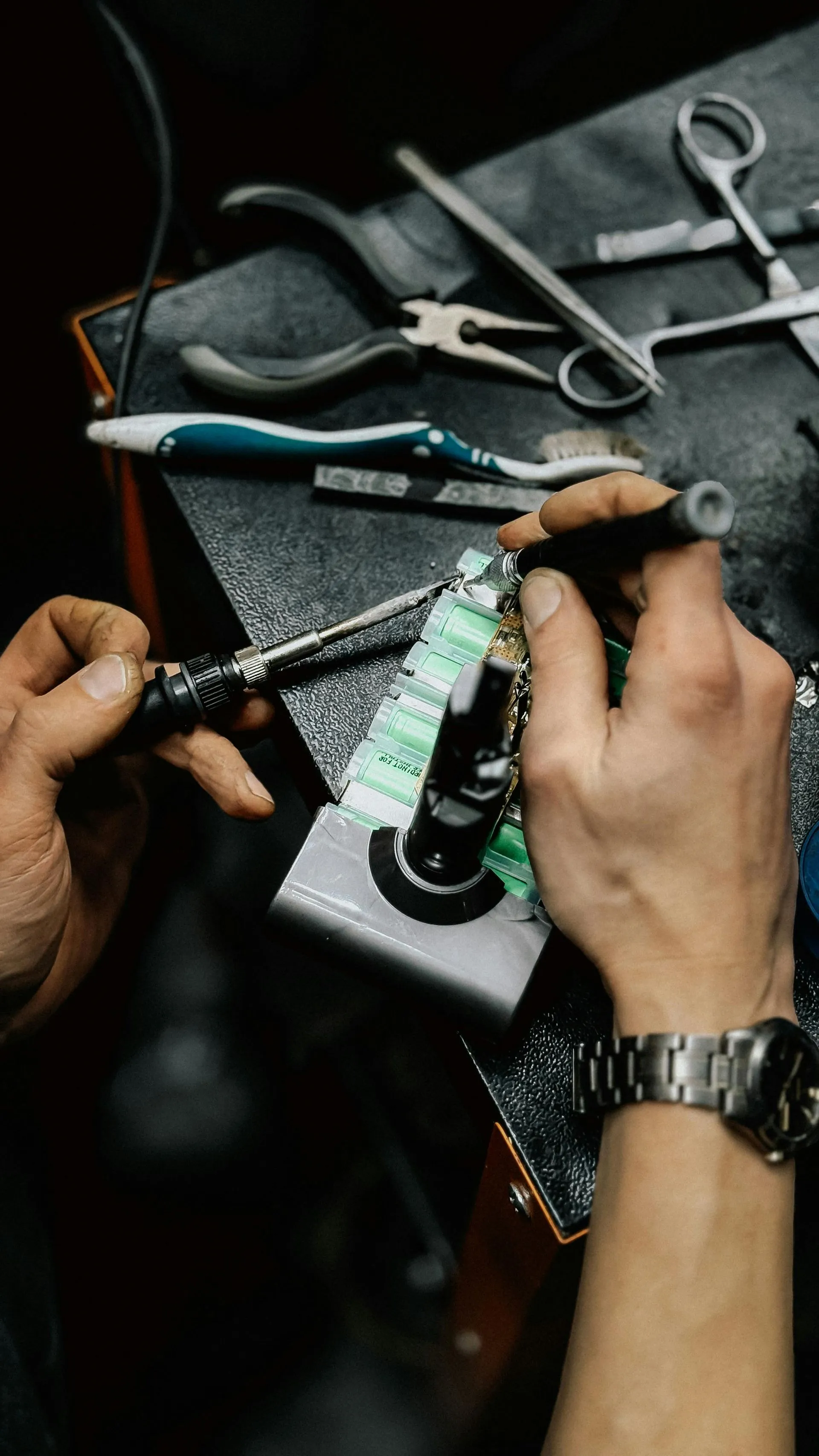 Technician repairing a battery pack with a precision screwdriver, hand tools on the bench