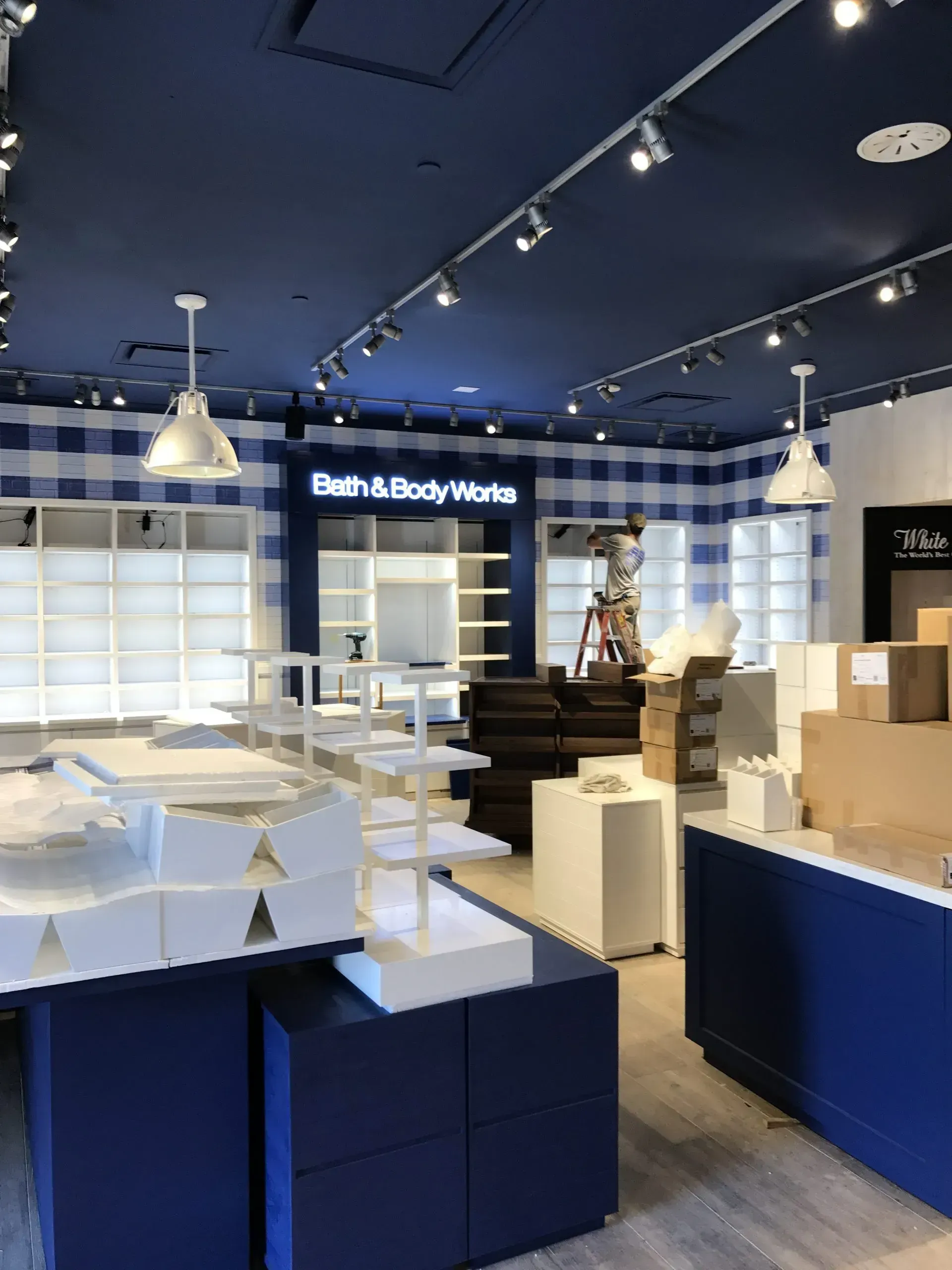 Bath & Body Works store interior with blue and white decor. Shelves, tables, and product displays are in place.