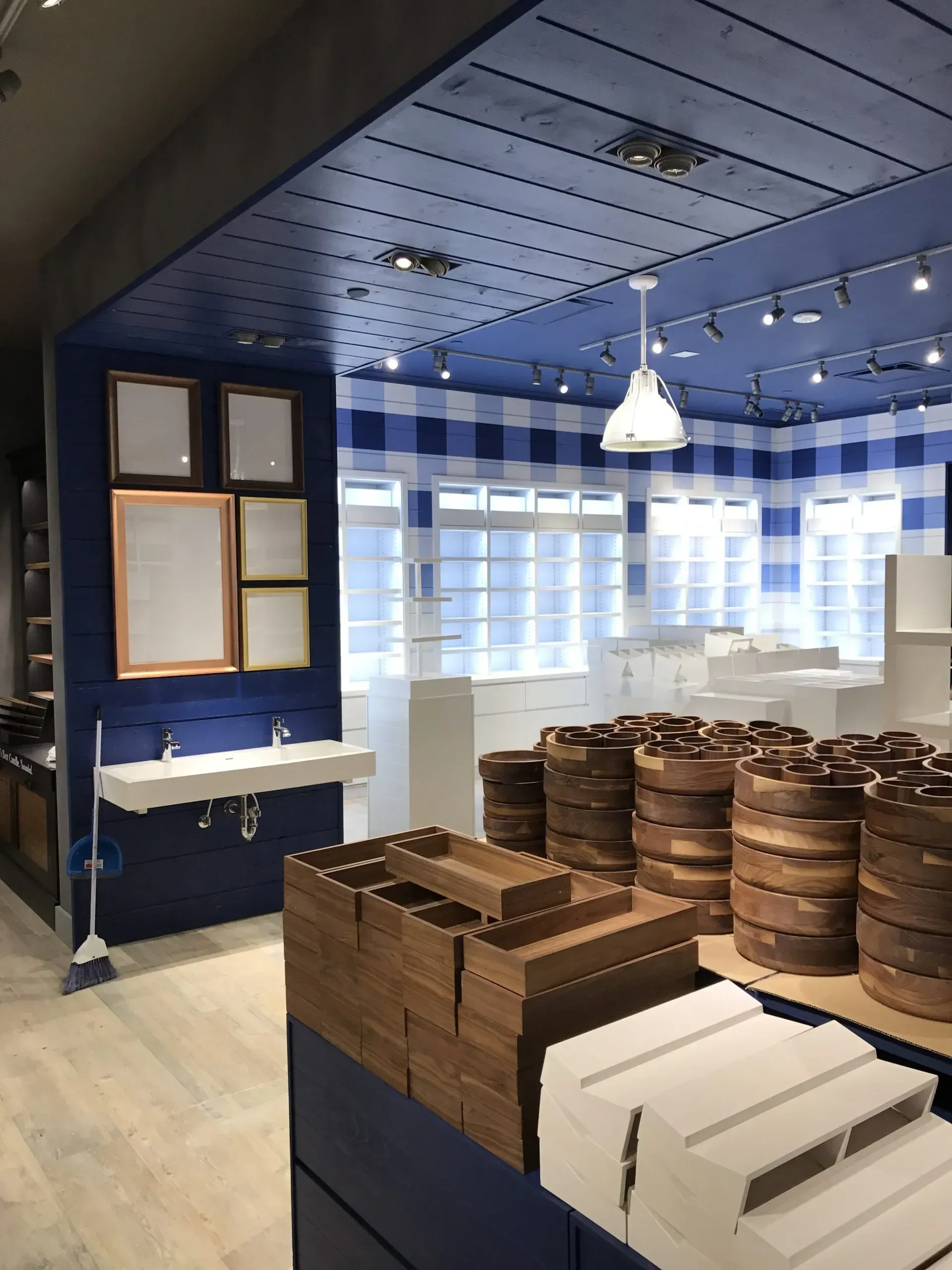 Inside Bath & Body Works store, blue walls, gingham pattern, wooden barrels, sinks, and empty frames.