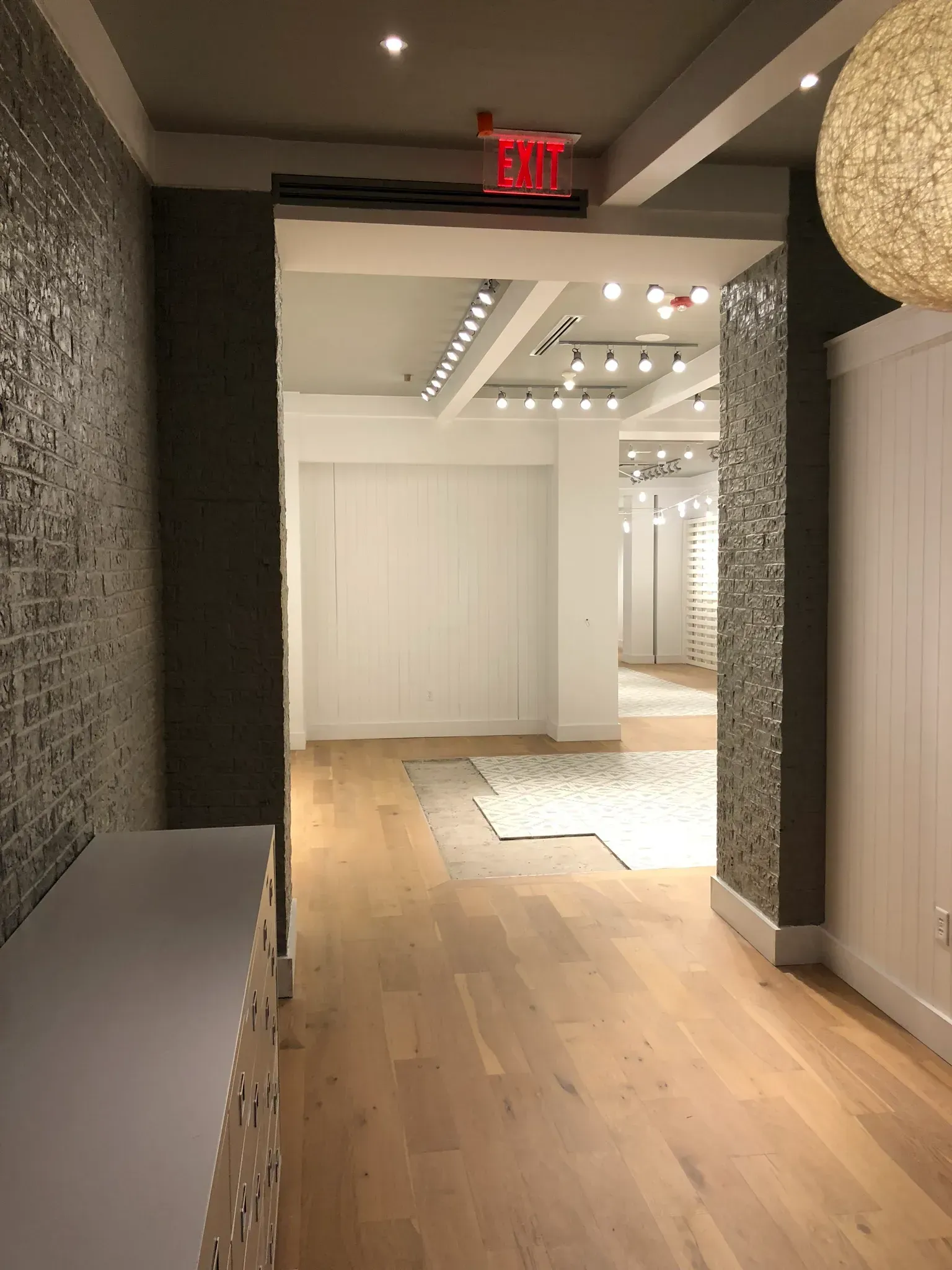Entrance hallway to a brightly lit retail space with hardwood floors and patterned walls.