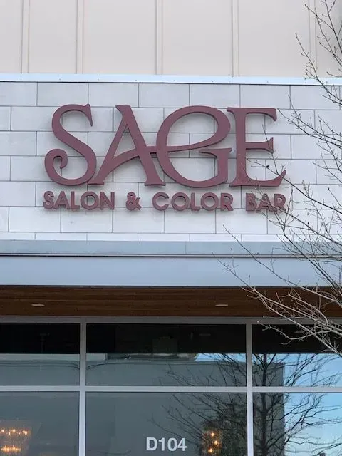 Sage Salon & Color Bar sign in mauve letters on a white brick storefront